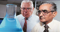 Dr. Mansukh Wani (right) and Dr. Monroe Wall (left) observe a beaker of camptothecin dissolved in chloroform and methanol, as it fluoresces in UV light.
